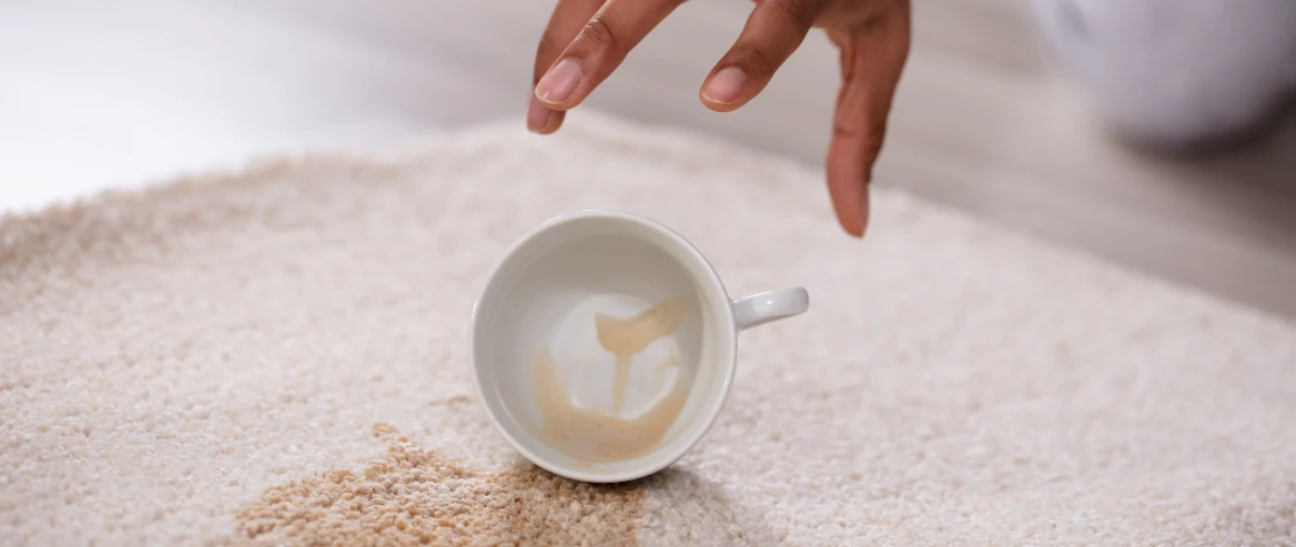 Hand Reaching Out To Pick Up Spilt Coffee Cup On Carpet