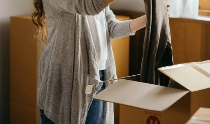 woman putting clothes on a box