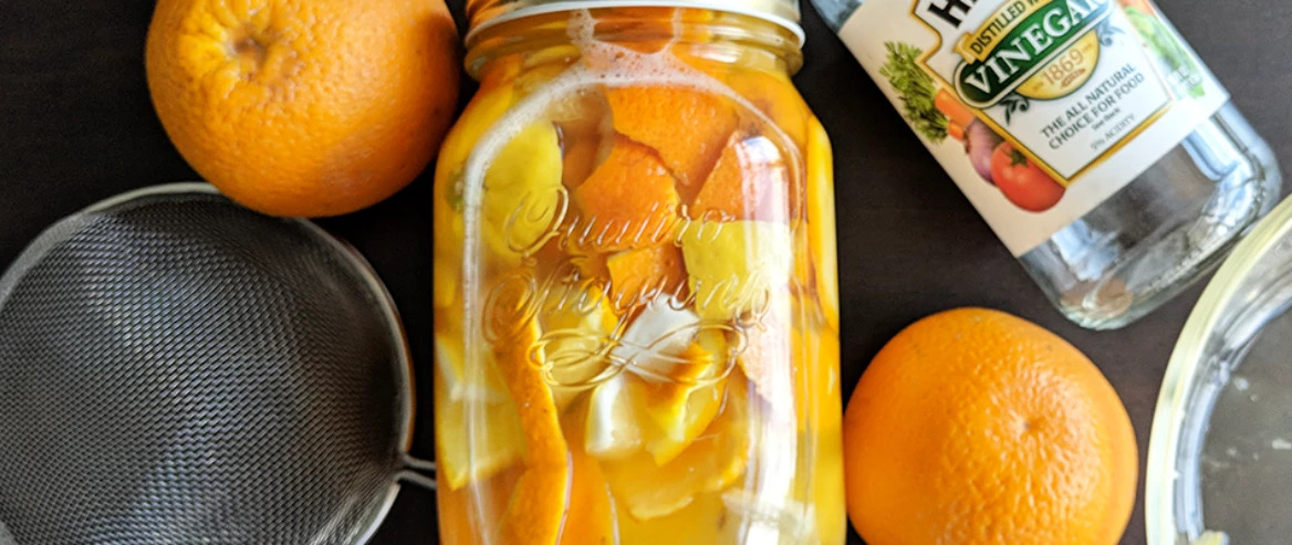Top View Of Bottle With Citrus Peelings Inside While Oranges Vinegar Bottle Strainer Around