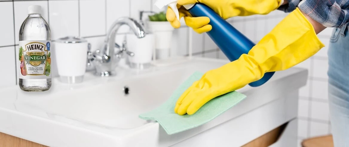 Woman Cleaning Bathroom Sink With Vinegar