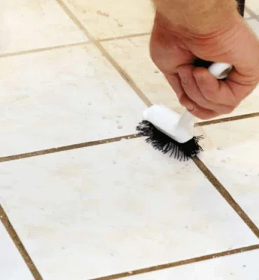 person on hands and knees scrubbing grout