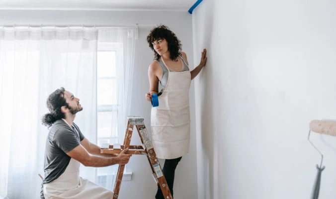 couple painting living room wall