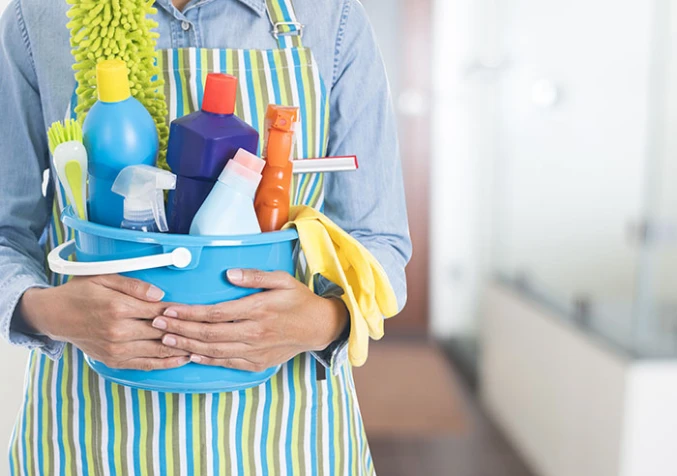 person holding bucket of cleaning supplies