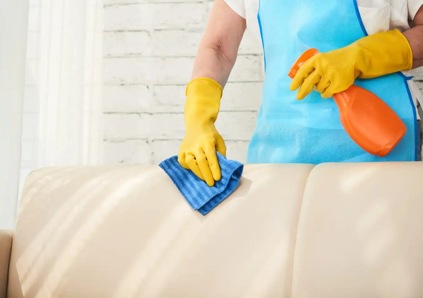 person wiping the couch with a cleaning spray