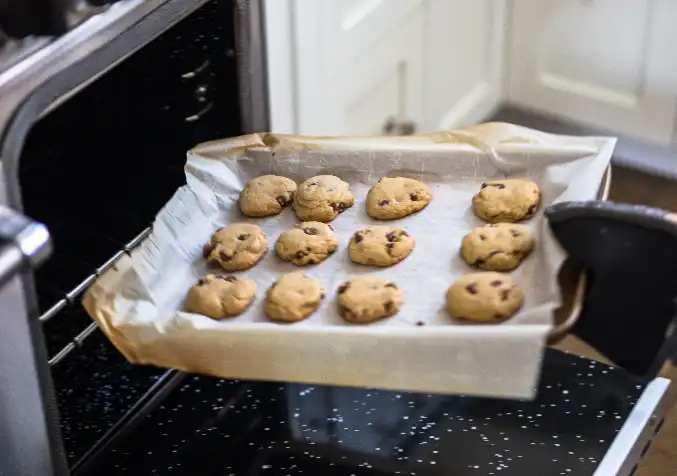 taking a tray of freshly baked cookies from the fridge