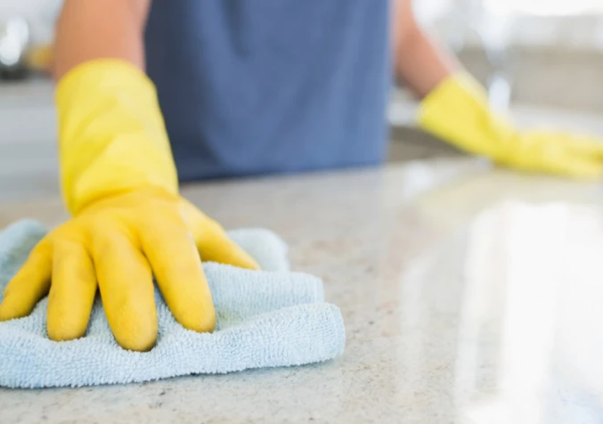 gloved hand wiping a kitchen top with a towel
