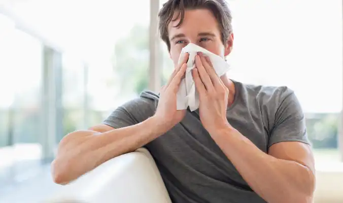 man covering nose to sneeze