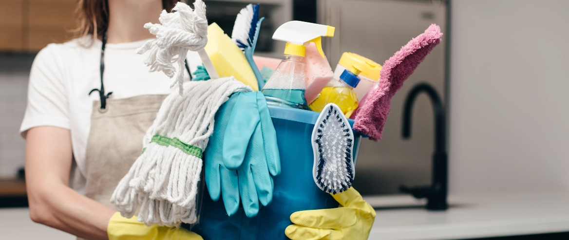 woman holding a bucket of cleaning materials