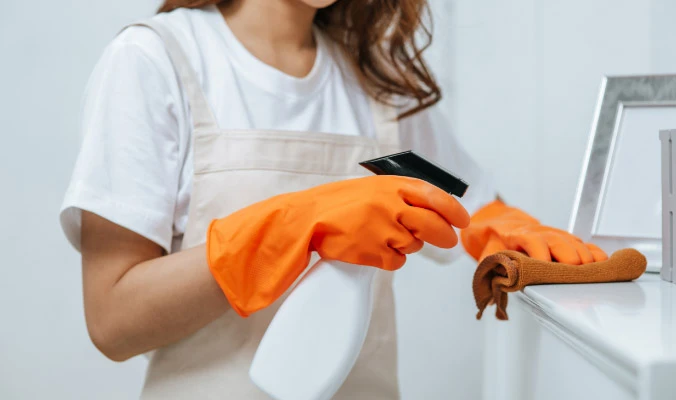 woman wearing gloves wiping cabinets