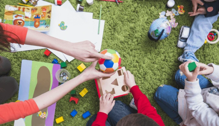 mother holding a colorful ball playing with her children