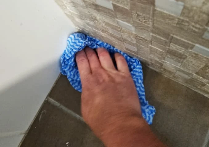 wiping grime from bathroom floor corner