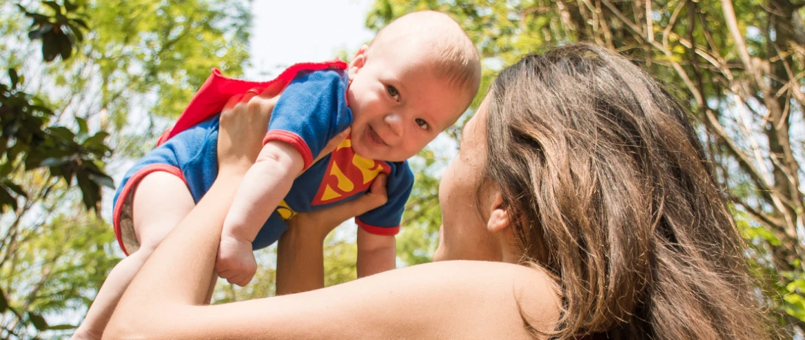 Woman Raising Baby In The Air In The Woods