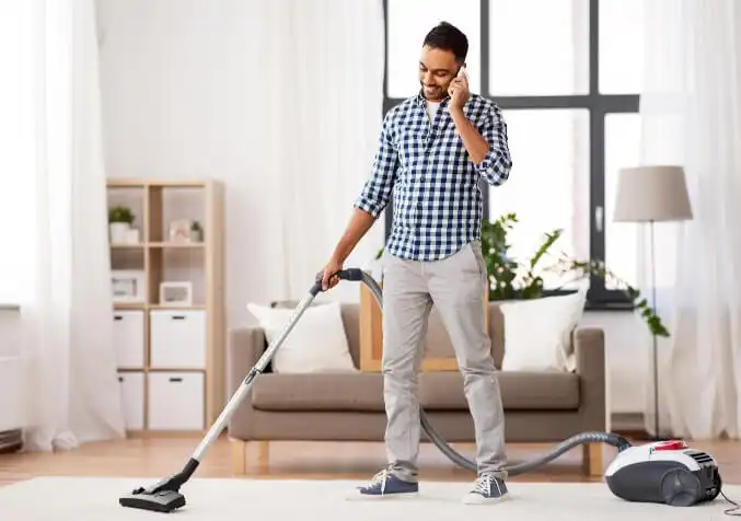 man vacuuming while on the phone