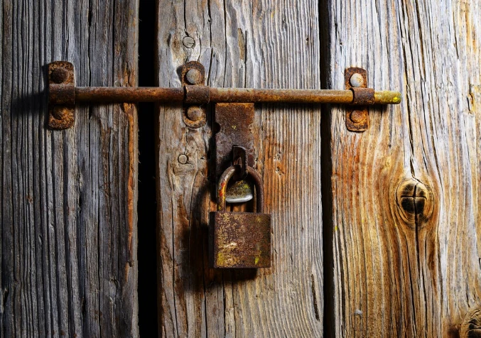 rusty padlock in a hook of an old wooden door