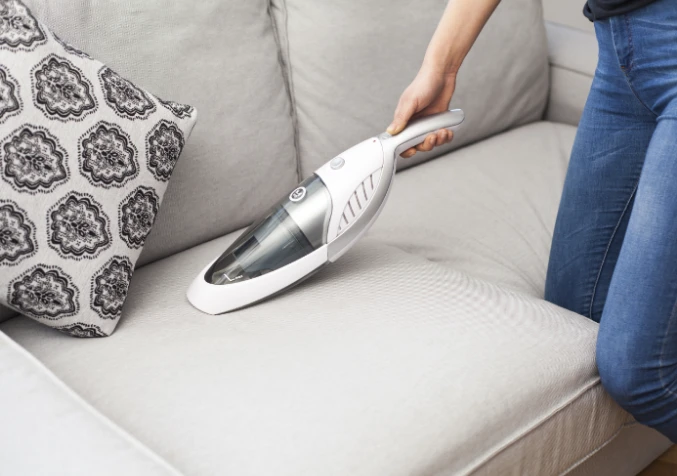 cleaning couch with a handheld vacuum cleaner