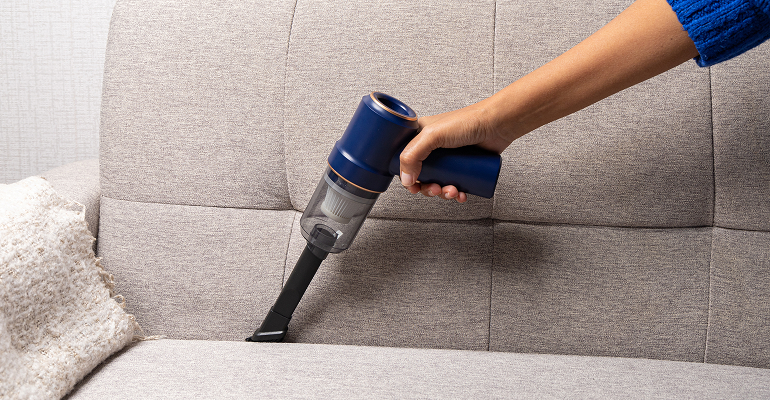 Close-up of a vacuum cleaner upholstery attachment cleaning sofa crevices