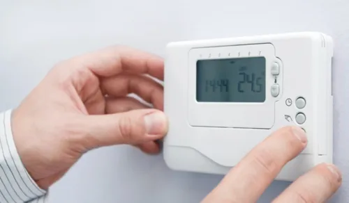 Setting air conditioner thermostat to 24 degrees for energy-efficient cooling.