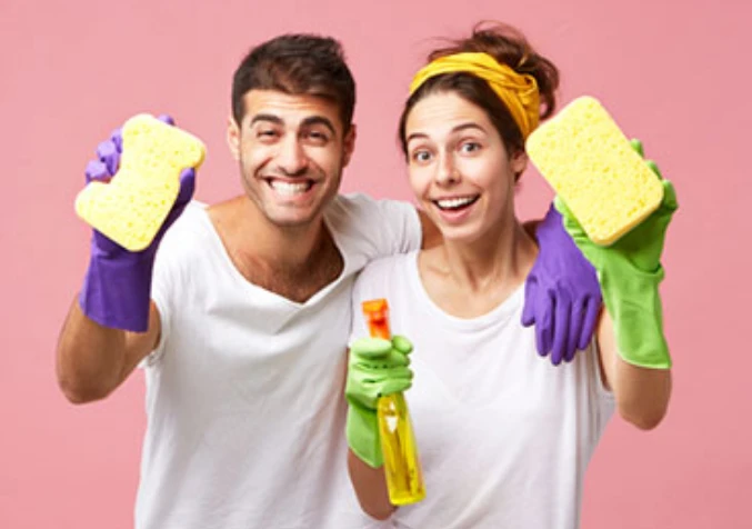 couple holding cleaning supplies