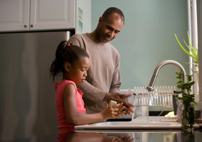 dad teaching little girl how to clean the dishes
