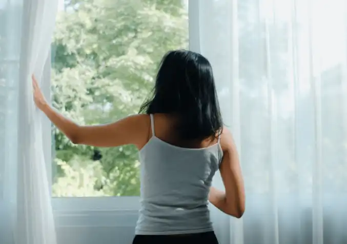 woman letting in fresh air by opening the window