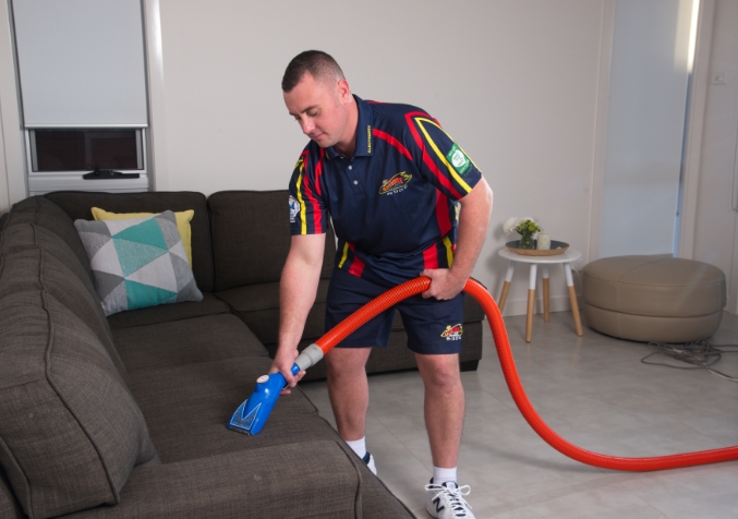 Electrodry technician performing professional upholstery cleaning on a fabric sofa.
