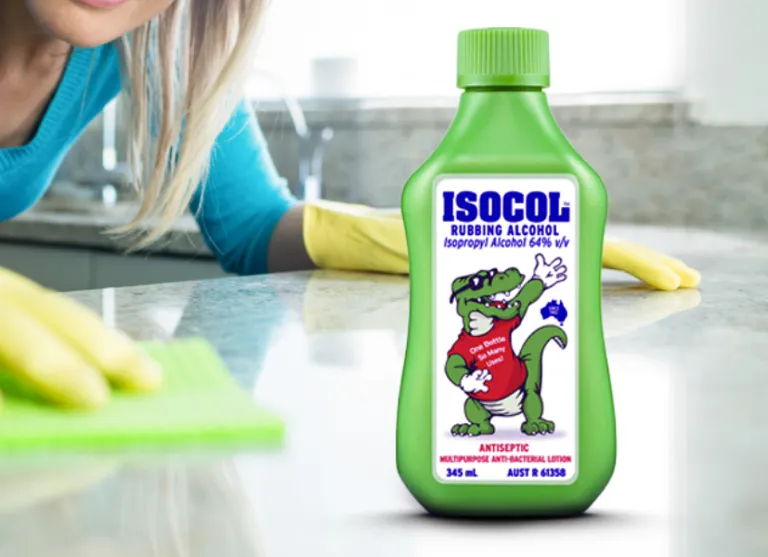 Person cleaning kitchen surface using rubbing alcohol spray bottle