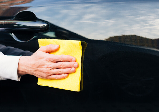 Polishing a light car paint scratch with a soft cloth.