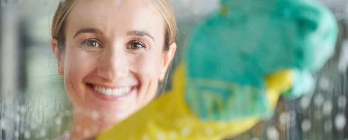 woman cleaning with gloves and sponge in bathroom