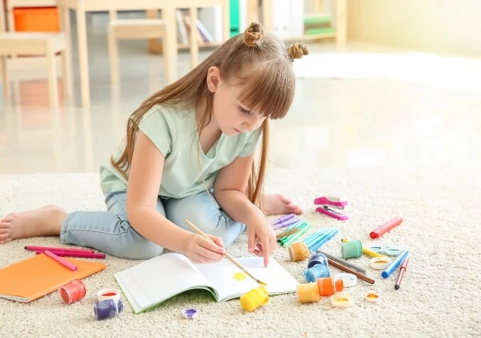 child drawing with paint on carpet