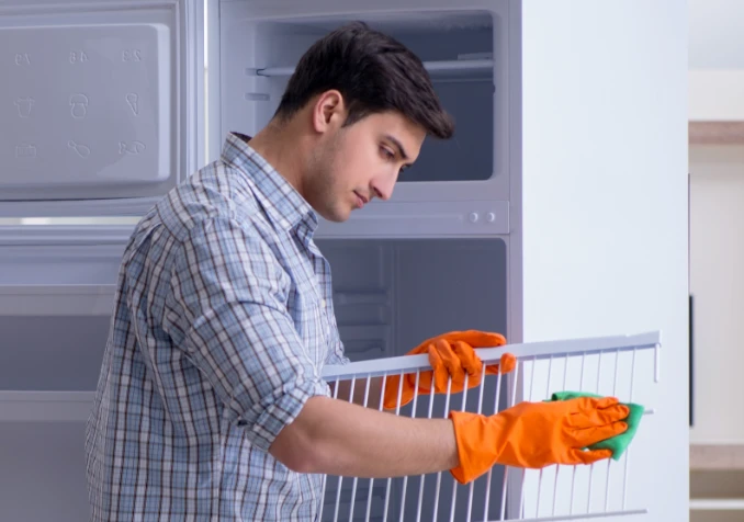 man cleaning fridge trays