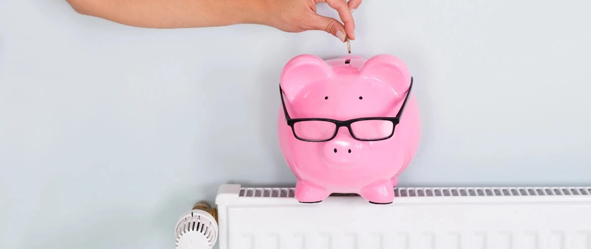 Hand Dropping Coin In A Ceramic Piggy Bank Placed On Top Of An Appliance