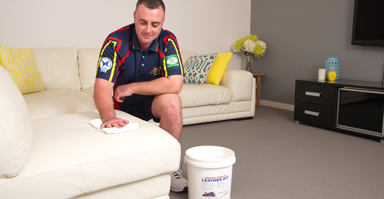 Technician professionally cleaning a fabric sofa with upholstery equipment