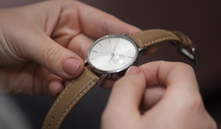 Gently wiping a watch face with a microfibre cloth to reduce fine surface marks.