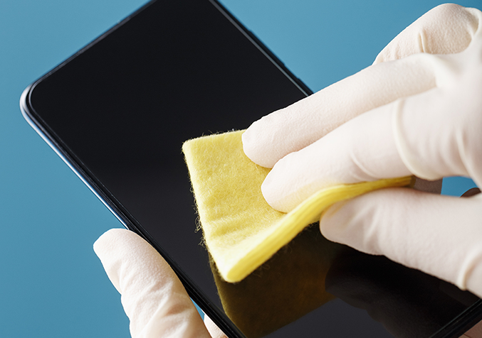 Person gently polishing a phone screen with a soft cloth to reduce light scratches.